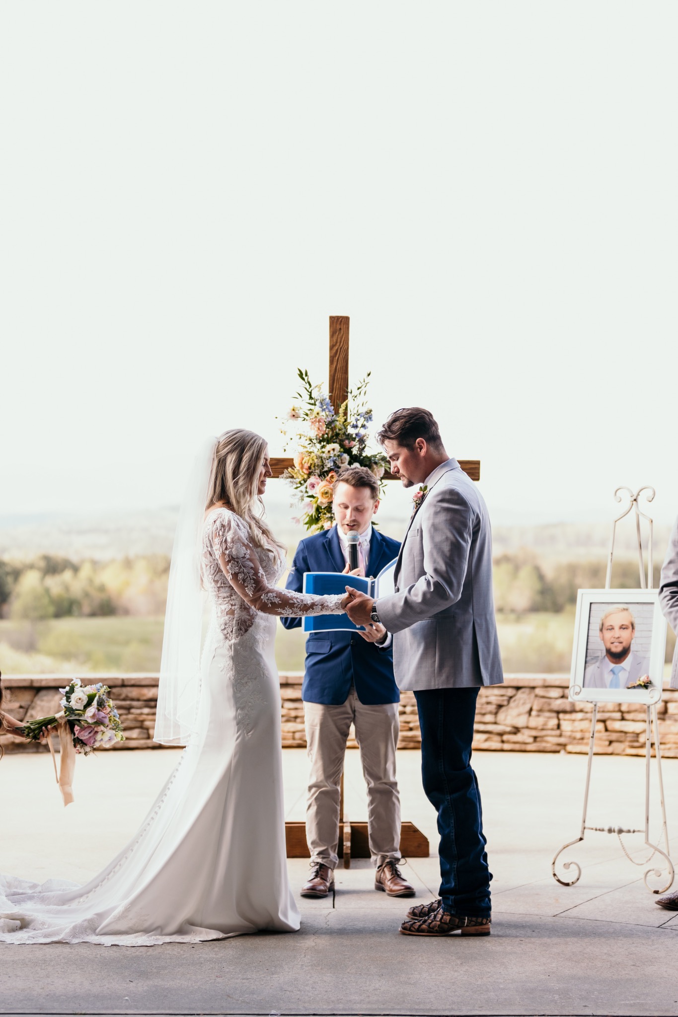 Derrick officiating a wedding ceremony before a floral cross